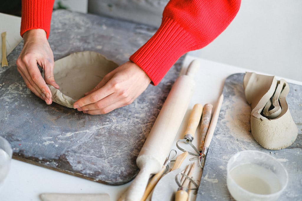 Crop woman molding clay on board